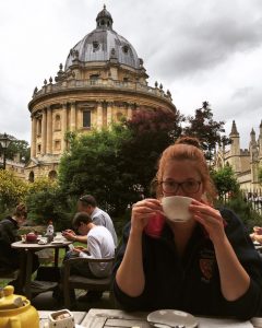 Student drinking tea with the Radcliffe Camera behind her